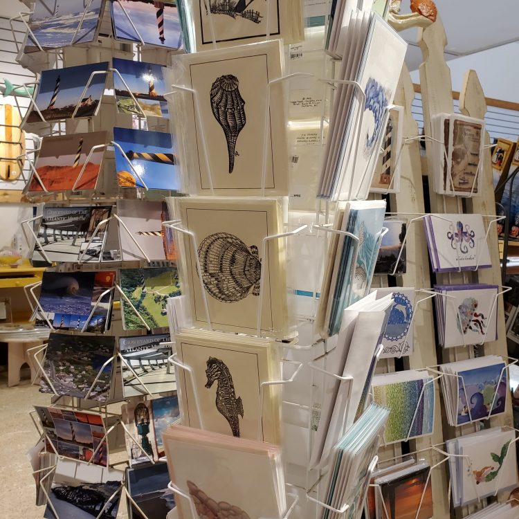 Display rack with various cards featuring sealife themed illustrations with postcards in the background