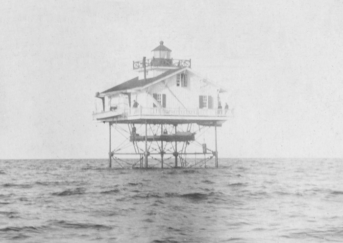a screw pile lighthouse is featured alone over a body of water