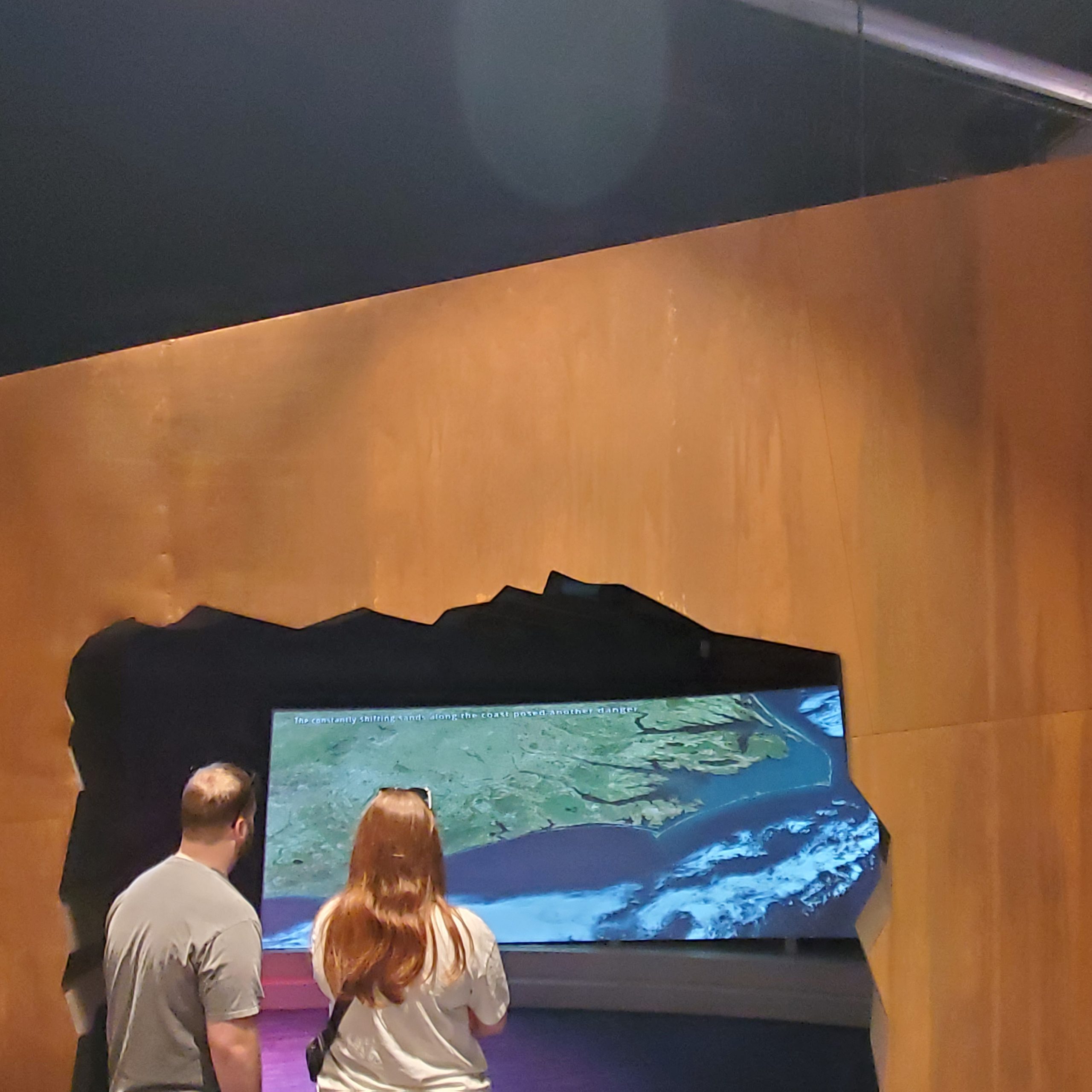 Two people look through a doorway at a video screen
